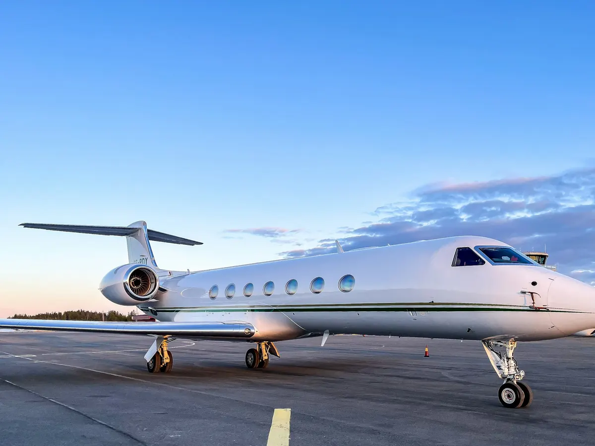 A large cabin jet parked on the ramp under a clear blue sky