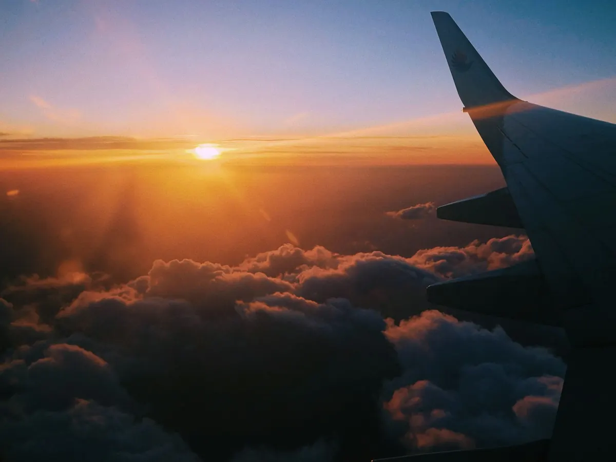 An aircraft wing above the clouds at sunset
